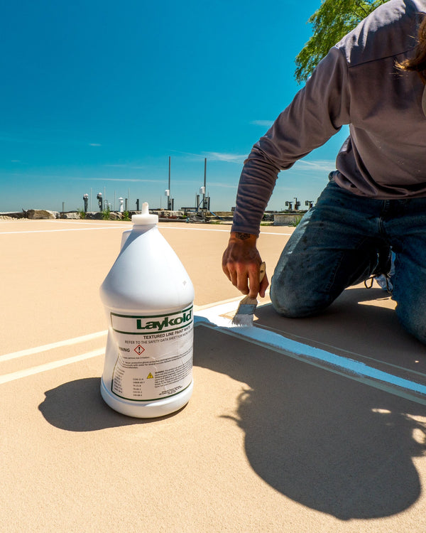 Installing Laykold Texturized White Line Paint on a desert sand colored, CLOUD cushion pickleball court.