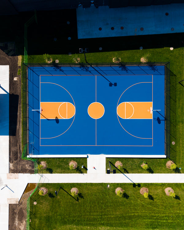 Community center basketball court coated with Laykold Dark Blue and Pumpkin in the key and game lines.