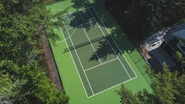 Cottage multi-use tennis court featuring EIGHTYNINE Sports tennis posts and net.